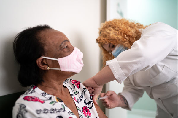 A photo of a woman receiving a COVID vaccine.