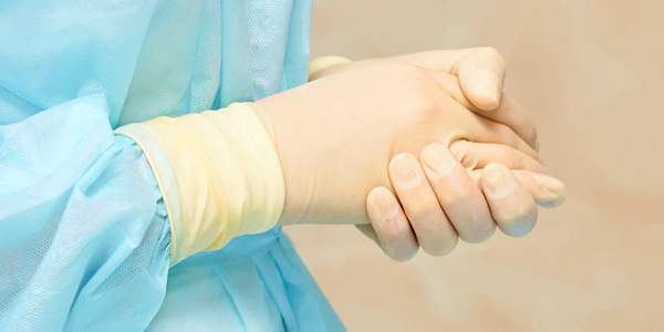 A photo of a person's hands showing gloves and gown.