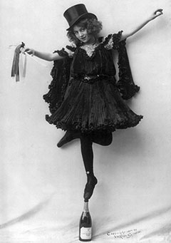 A woman standing tip-toed on a champagne bottle.
