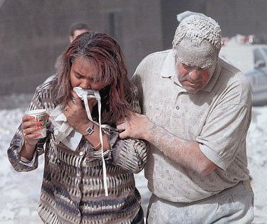 A photo of a man covered with dust assisting a woman after the 911 World Trade Tower attack.