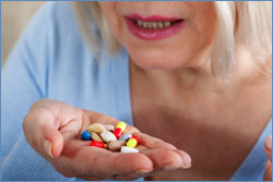 A photo of a woman with a handful of pills.