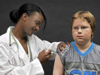 Nurse giving a vaccine to a young boy.
