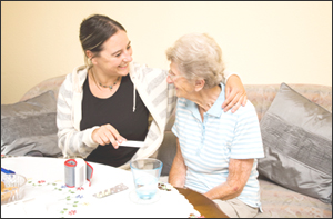A home health aide assisting an older woman with her medications.