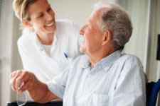 An aide helps an older man get ready for breakfast.