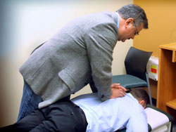 A chiropractor demonstrating an adjustment on the patient’s thoracic spine. 