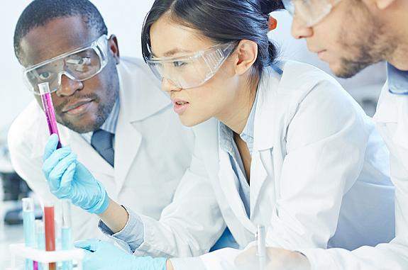 Three scientists examining a test tube.